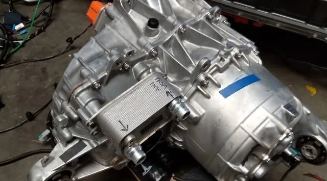 Tesla Model 3 drive unit with heat exchanger removed for service at TSK