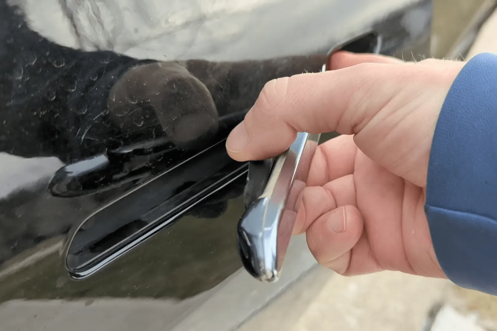 Technician holding Tesla Model 3 chrome door handle during exterior repair service
