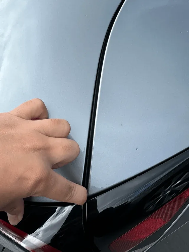 Technician checking panel gap alignment on Tesla Model 3 rear quarter panel
