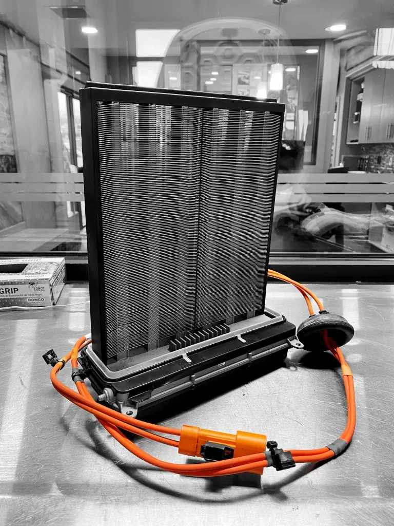 Tesla Model 3 cabin heater core with orange high-voltage connectors on shop bench