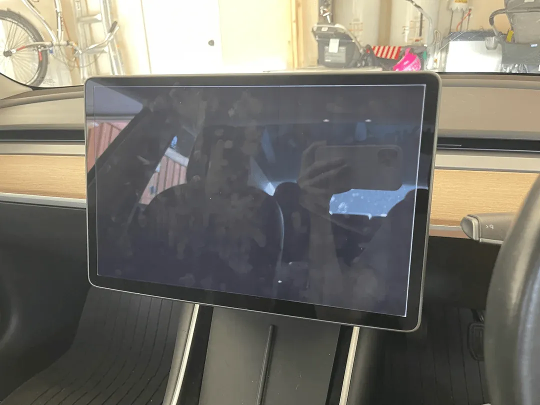 Tesla Model 3 center touchscreen displaying a dark, unresponsive MCU screen before repair