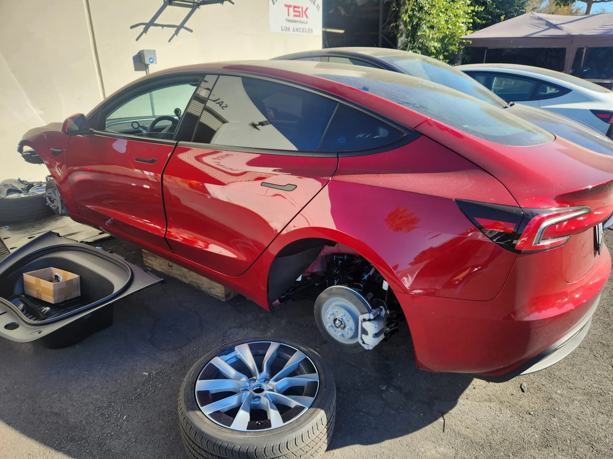 Red Tesla Model 3 rear wheel removed during brake service at TSK