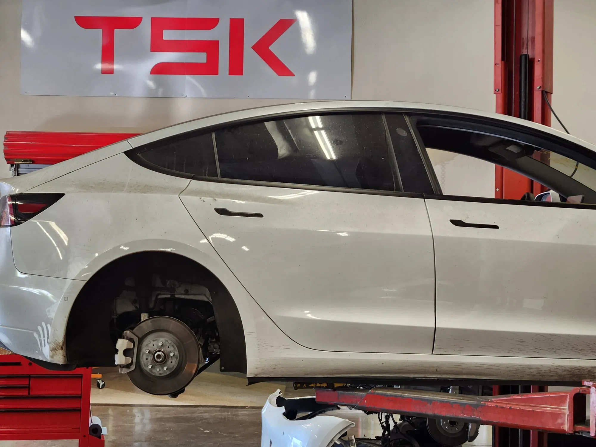 White Tesla Model 3 on lift with front wheel removed exposing brake rotor at TSK
