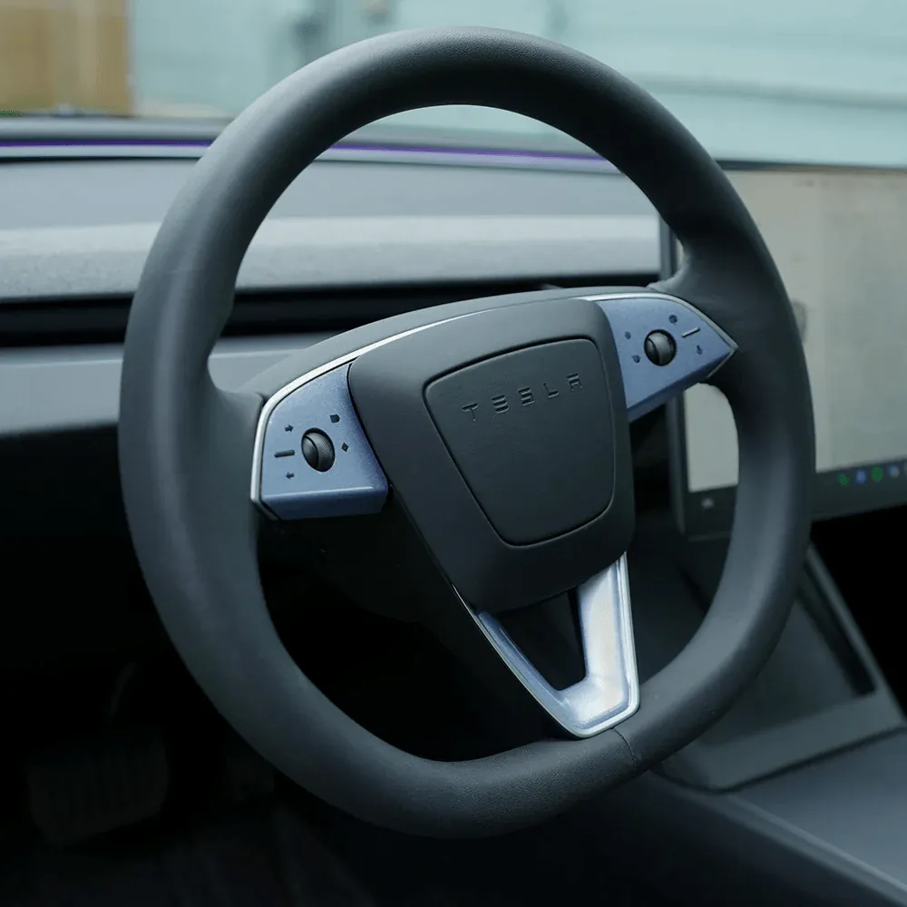 Tesla Model 3 steering wheel with round yoke design and blue-gray control buttons