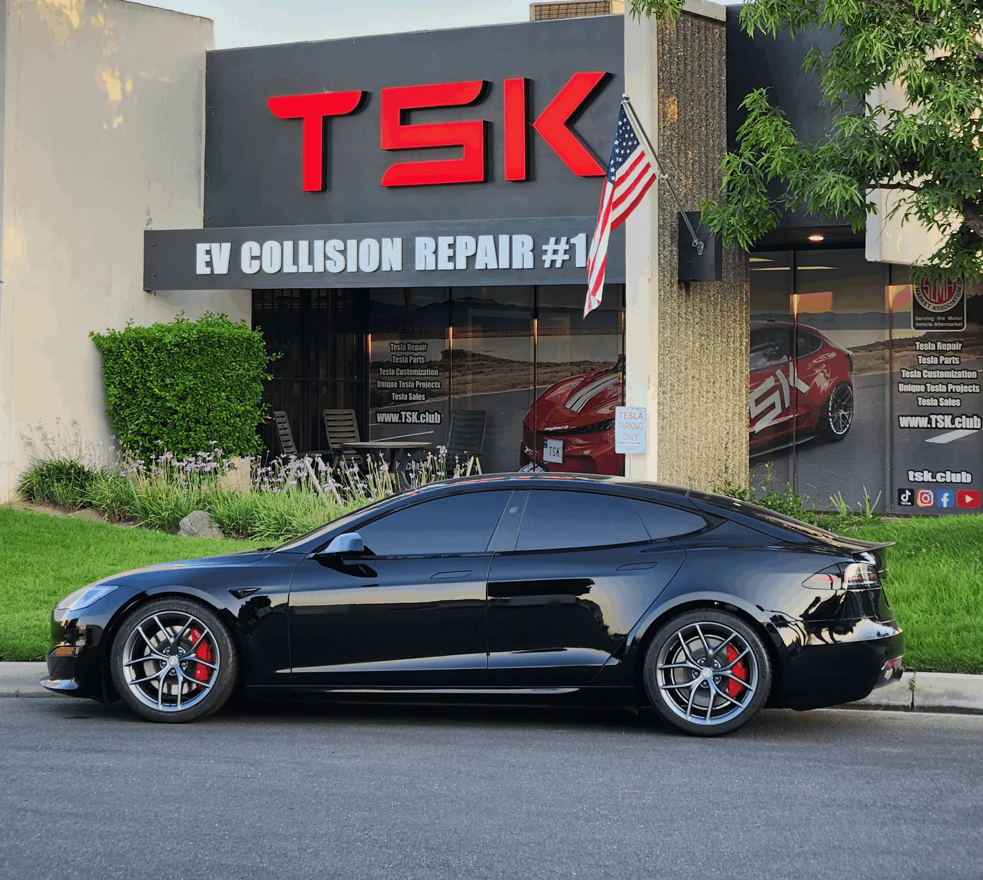 Black Tesla Model S with custom wheels parked outside TSK EV Collision Repair shop