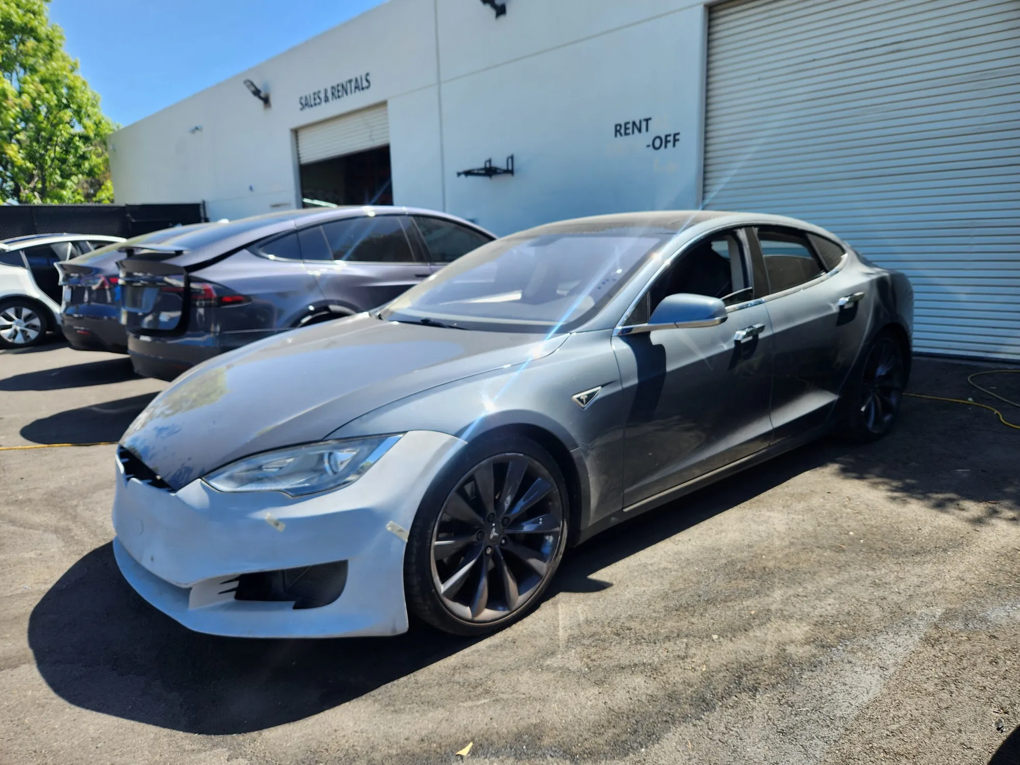 Silver Tesla Model S with damaged front bumper at TSK collision repair lot