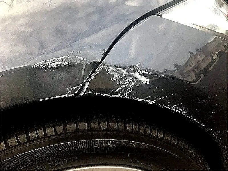 Scuffed paint and scratches on Tesla Model S front fender near wheel