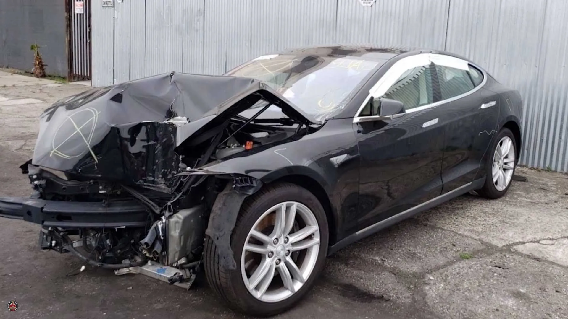 Black Tesla Model S with severe front-end collision damage before frame straightening at TSK