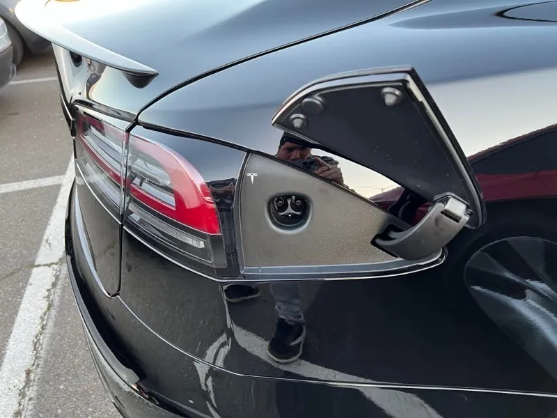 Open charge port with door on black Tesla Model S during inspection at TSK
