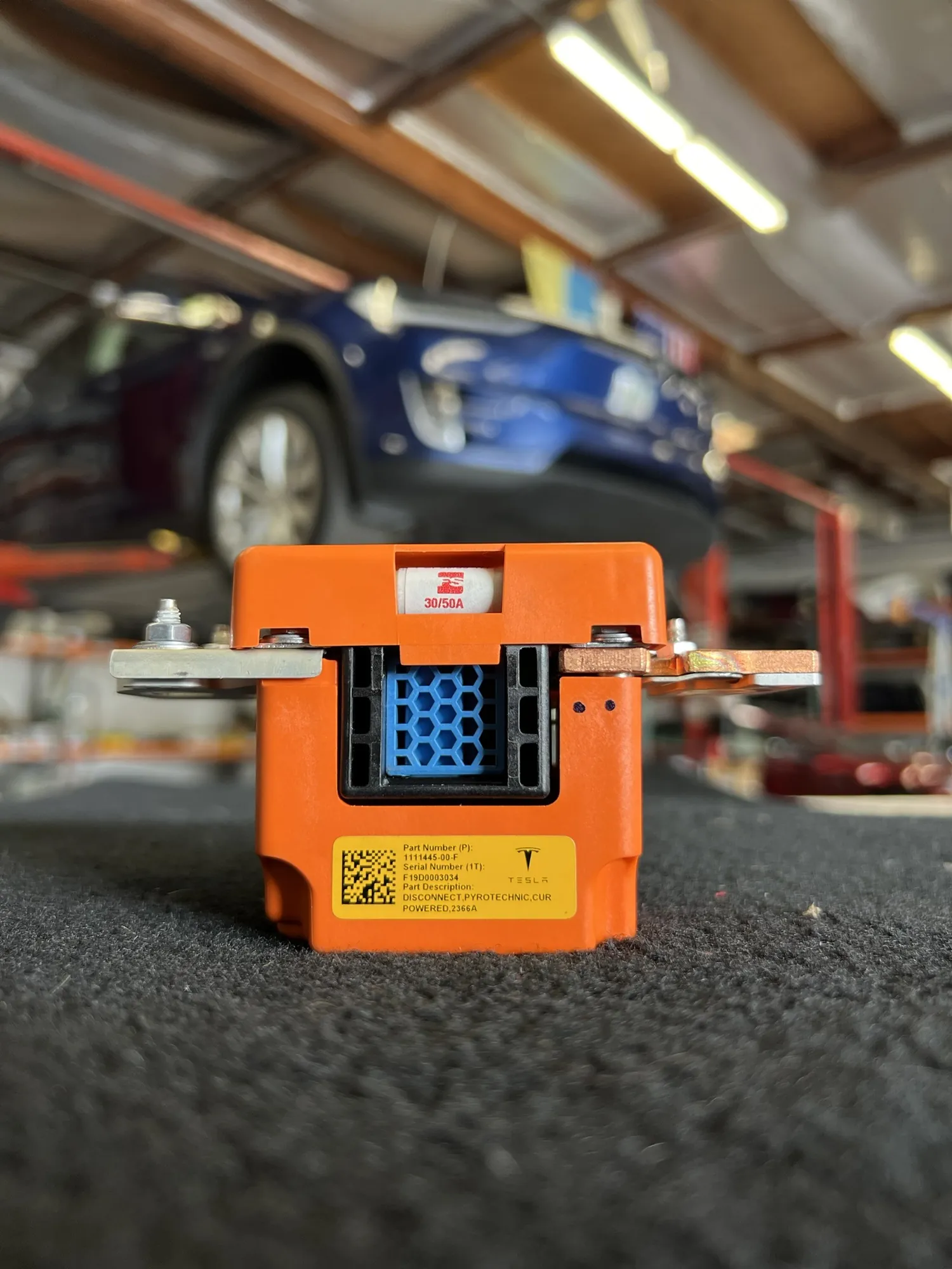 Tesla pyrotechnic disconnect fuse module removed for charging system diagnosis at TSK