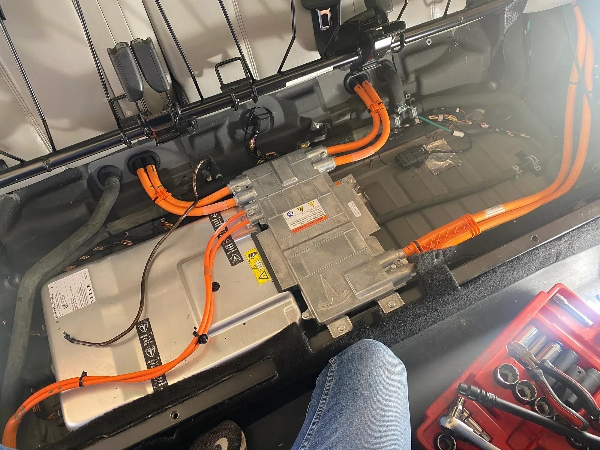 Tesla Model S onboard charger with orange high-voltage cables during charging system repair at TSK