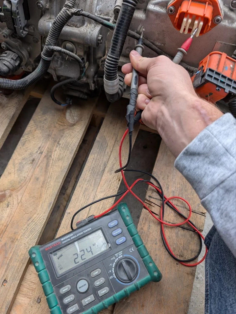 Technician using digital insulation tester on Tesla Model S drive unit wiring