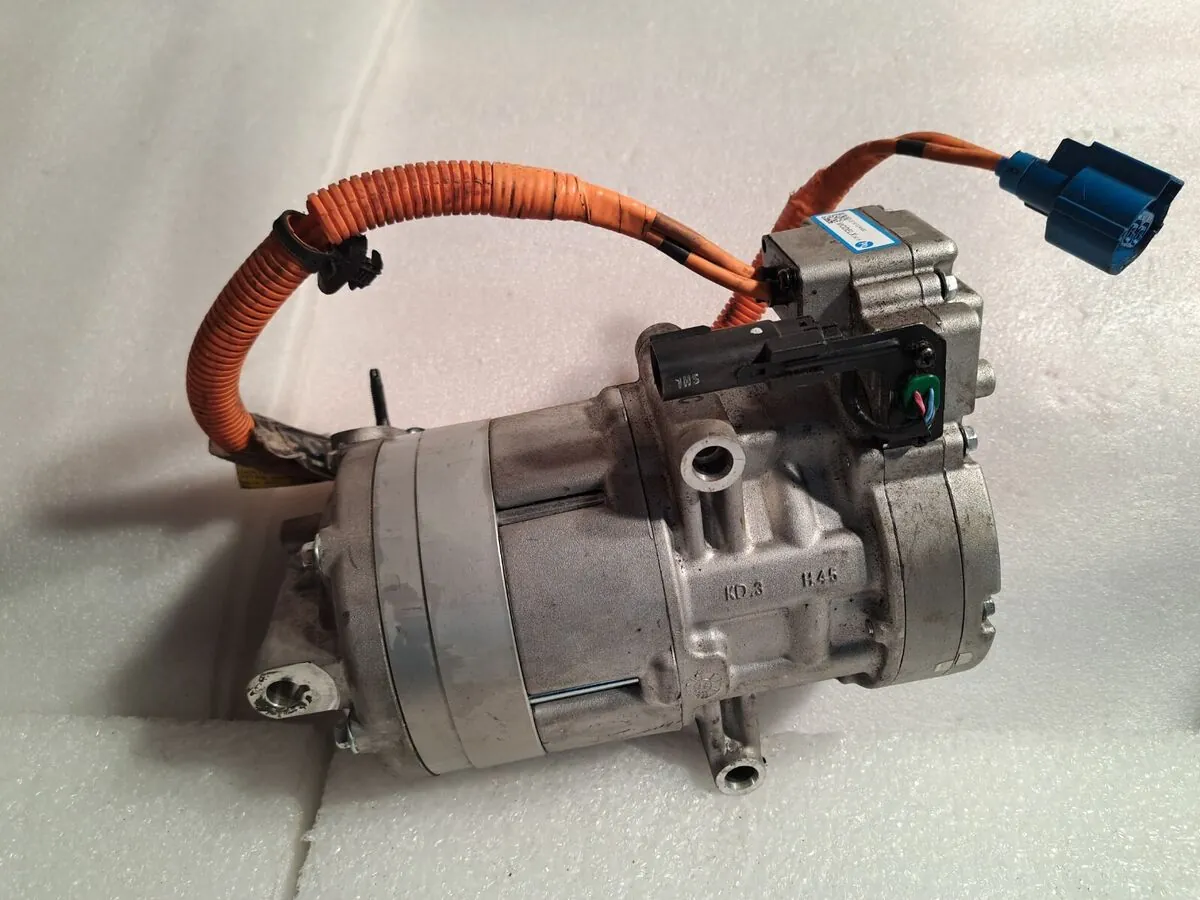 Tesla Model S electric AC compressor with orange high-voltage cable, removed for repair