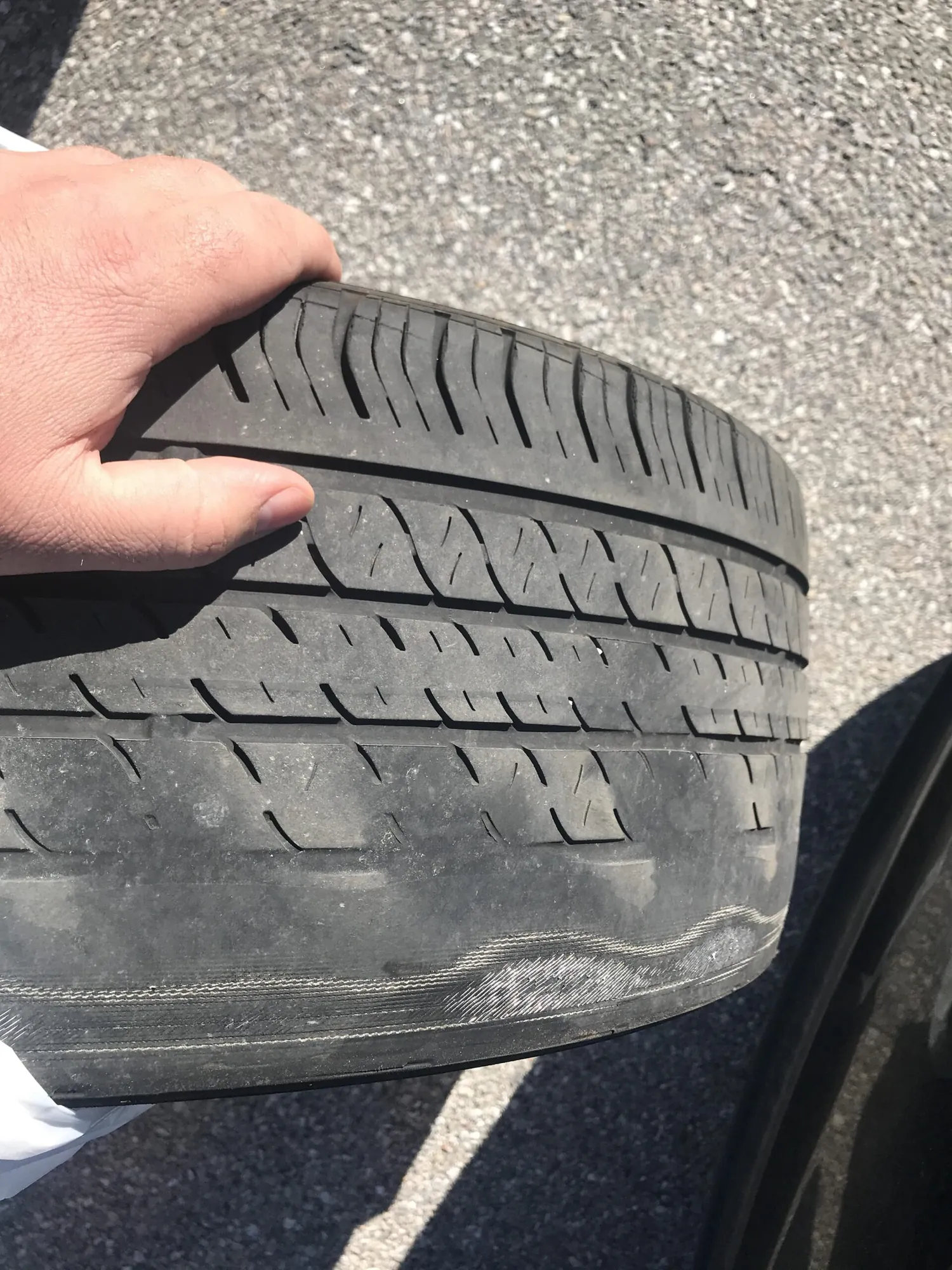 Technician inspecting worn tire tread on a Tesla Model S at TSK