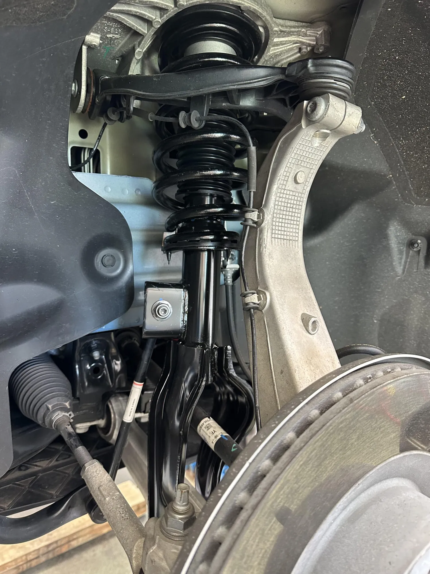 Tesla Model S front suspension strut, coil spring, and control arm close-up