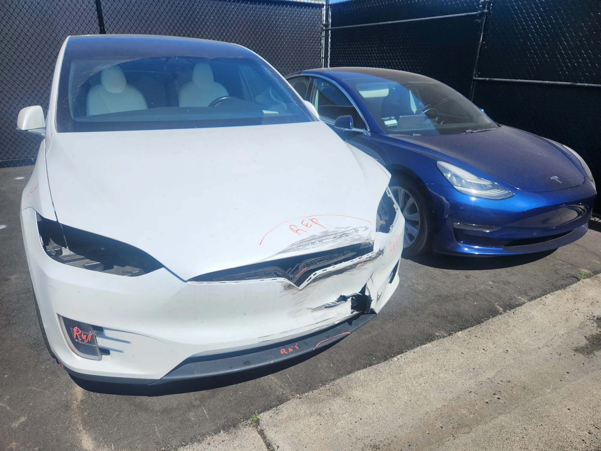 White Tesla Model X with damaged front bumper marked for repair at TSK