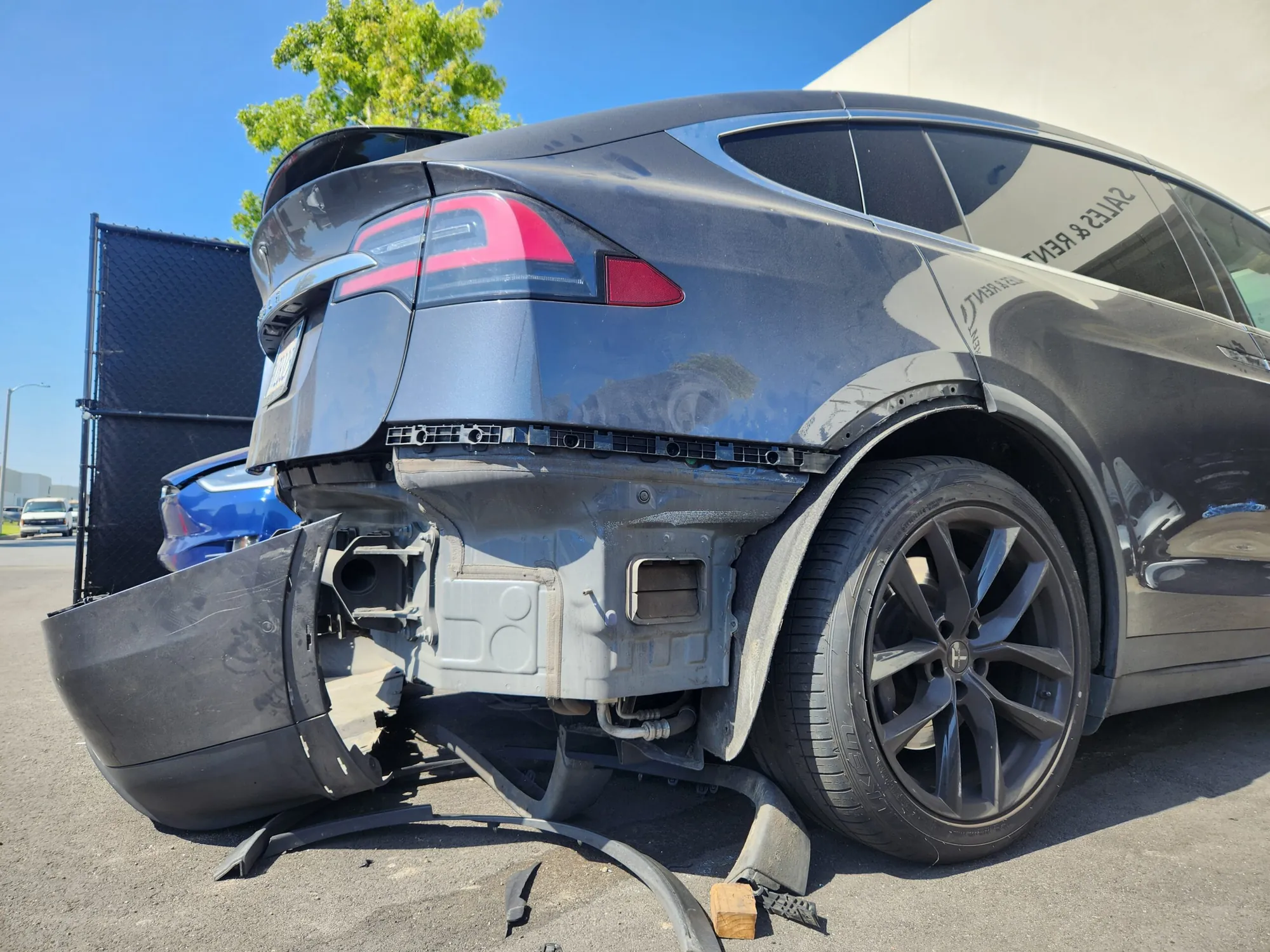 Tesla Model X with damaged rear bumper detached, exposing structure before body repair