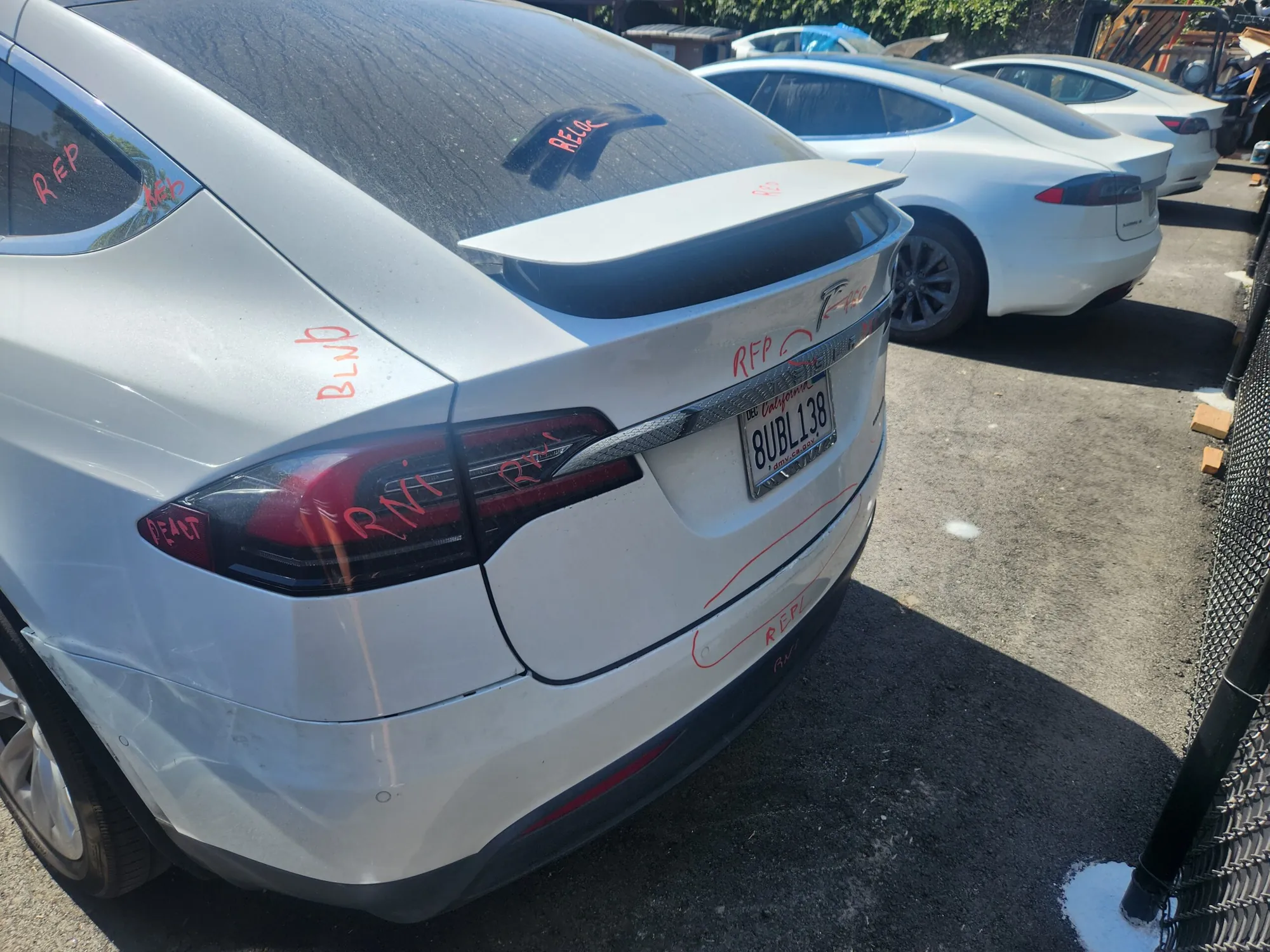 Silver Tesla Model X rear bumper with damage markings at TSK body shop
