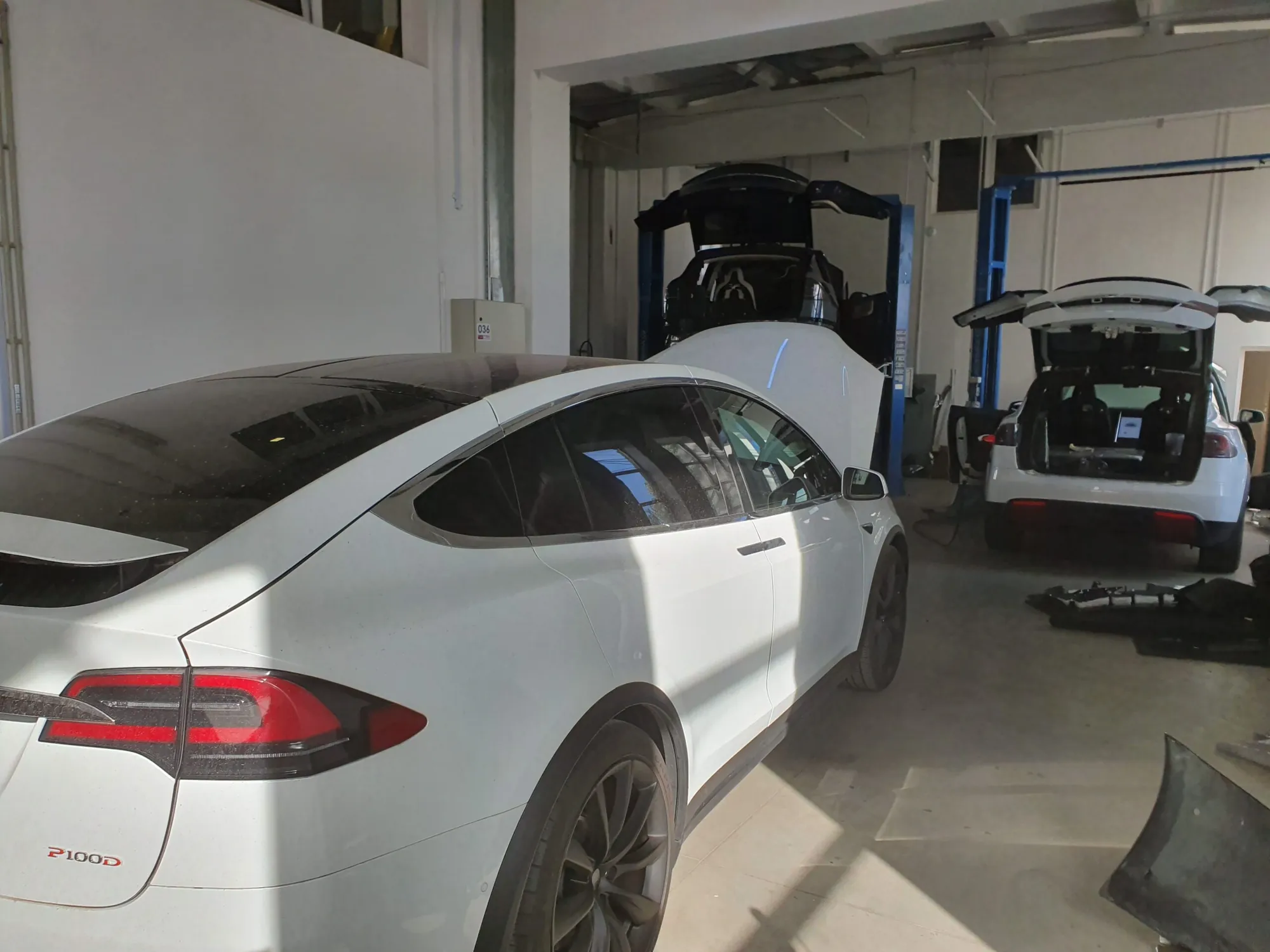 White Tesla Model X P100D in TSK body shop with other Model X units under repair