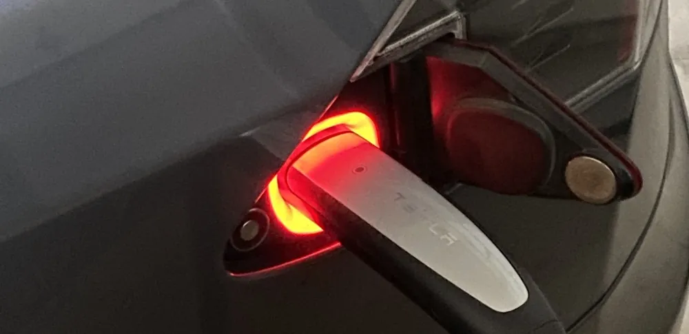 Tesla charge port glowing red, indicating charging fault needing troubleshooting