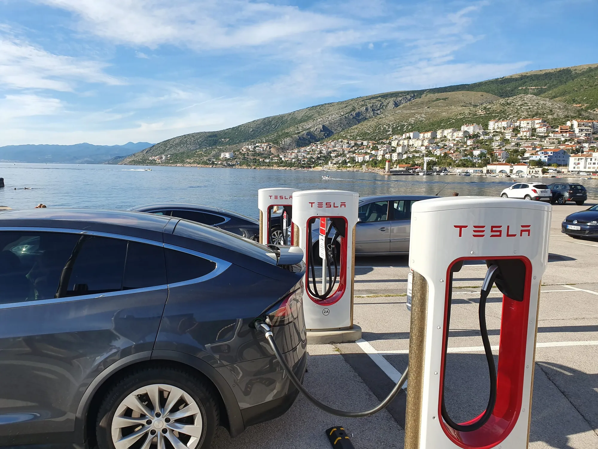 Tesla Model X plugged into a Supercharger at a coastal charging station