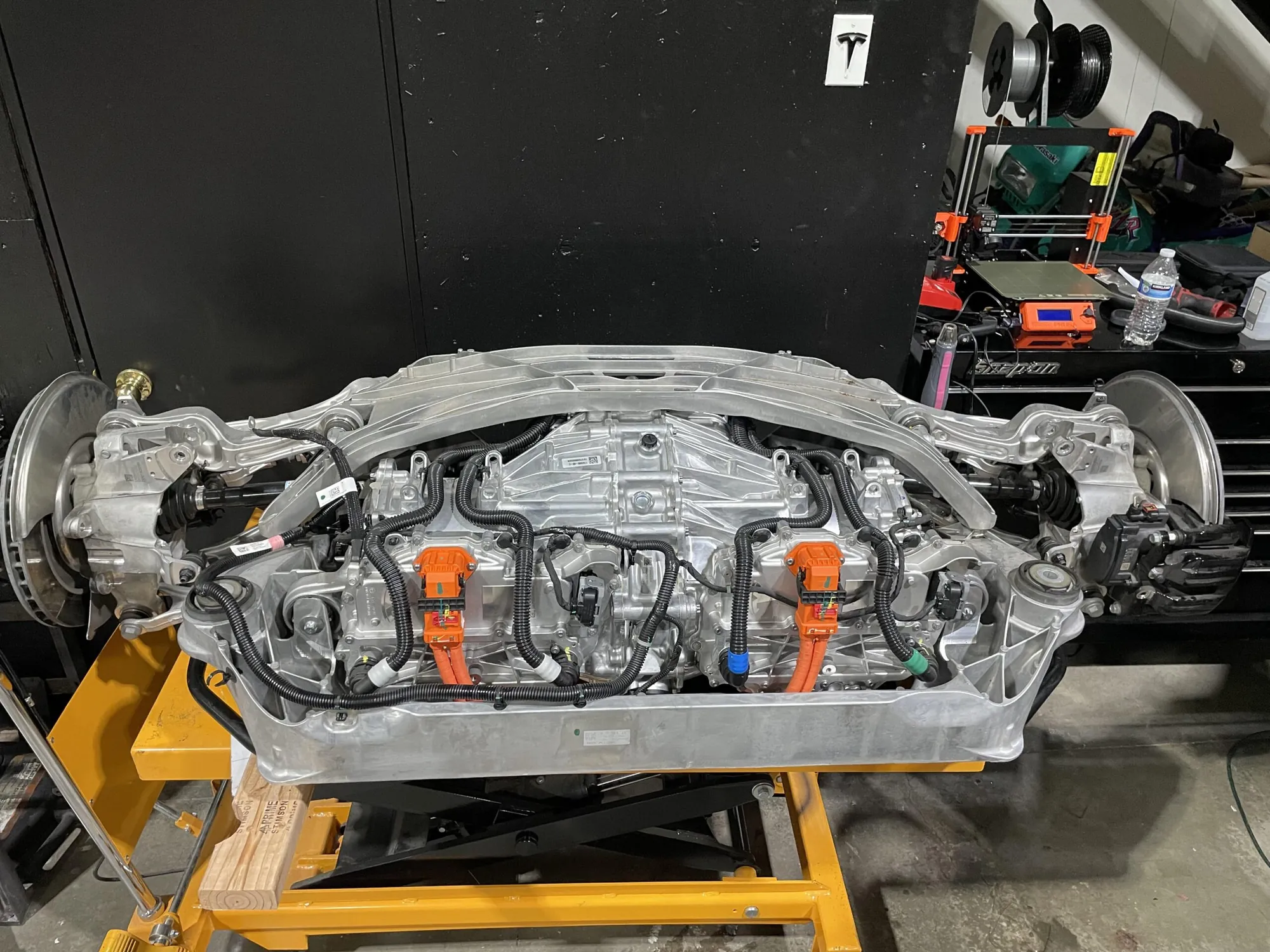 Tesla Model X rear drive unit with axles removed on shop lift at TSK