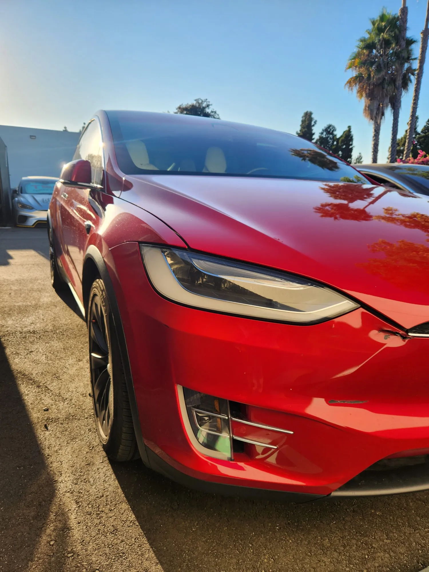 Close-up of red Tesla Model X front headlight and fender after exterior repair at TSK