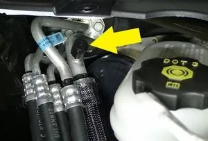 Tesla Model X AC hose fittings near brake fluid reservoir during HVAC service