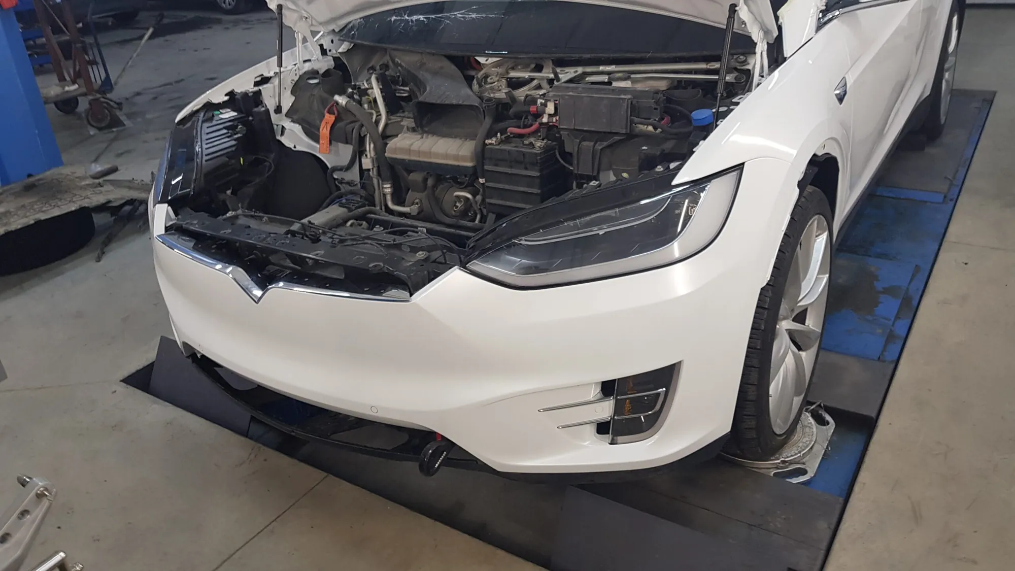 White Tesla Model X with open hood exposing front trunk and HVAC components at TSK