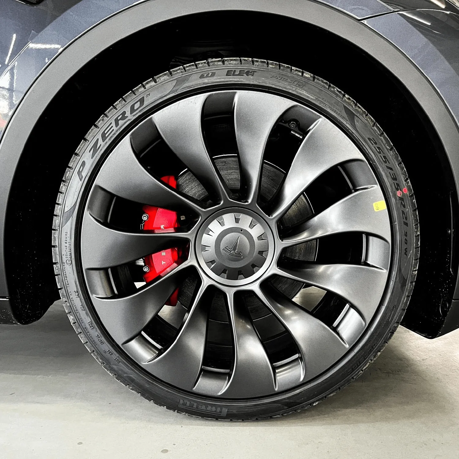 Tesla wheel with red brake calipers and Pirelli P Zero tire, close-up view