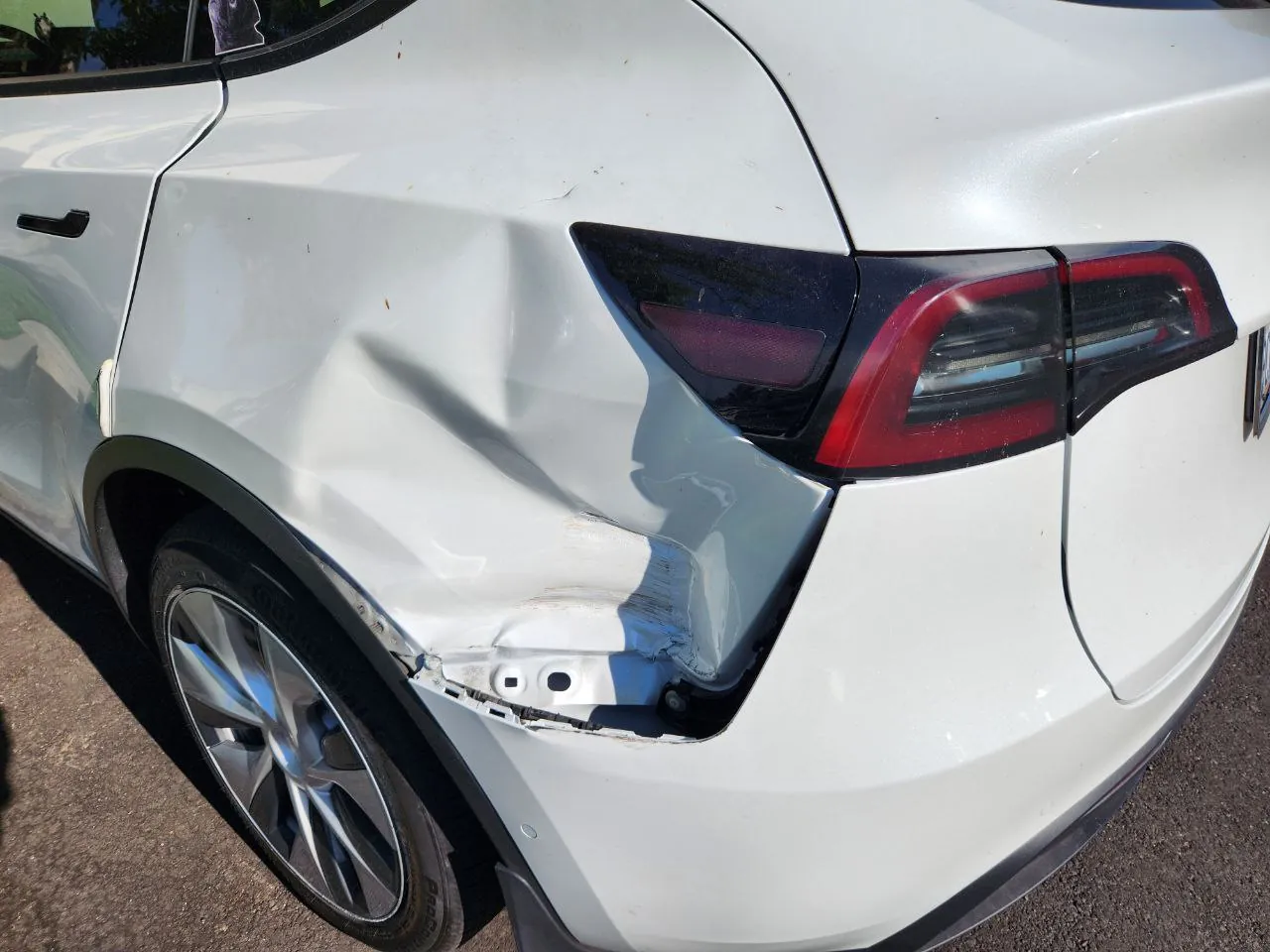 White Tesla Model Y with crushed rear quarter panel and taillight damage before repair