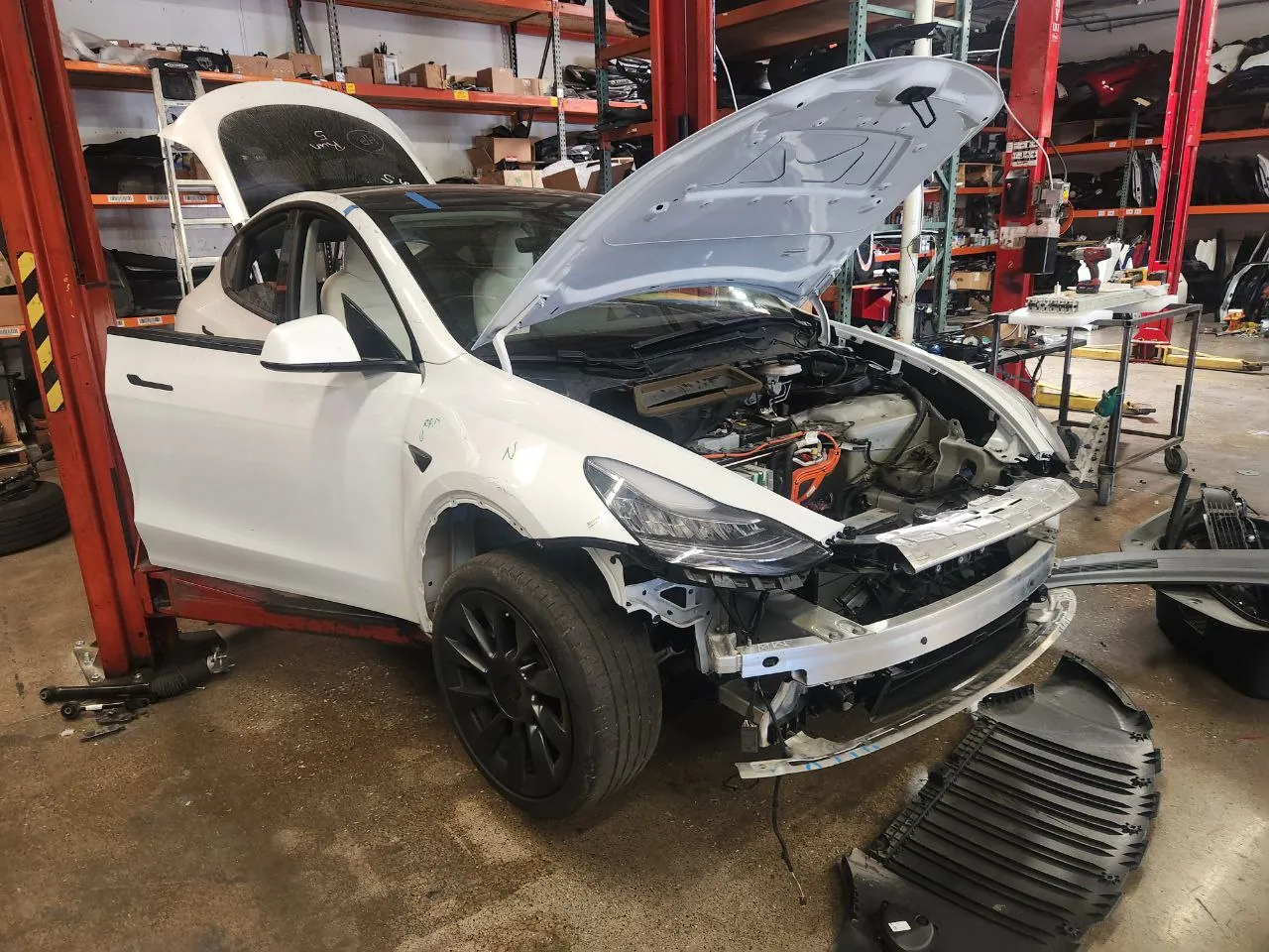 White Tesla Model Y with front bumper removed during body repair at TSK