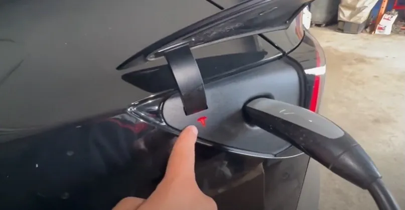 Technician pointing to Tesla Model Y charge port with connector plugged in