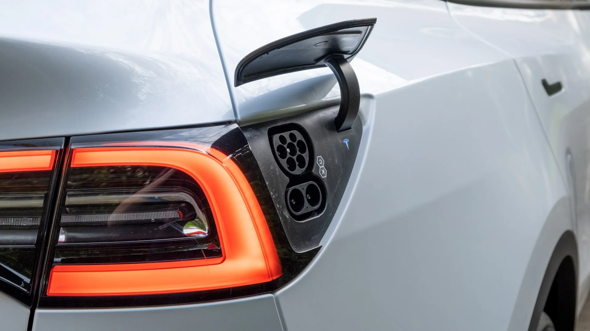 Tesla Model Y open charging port with taillight illuminated during diagnostics inspection