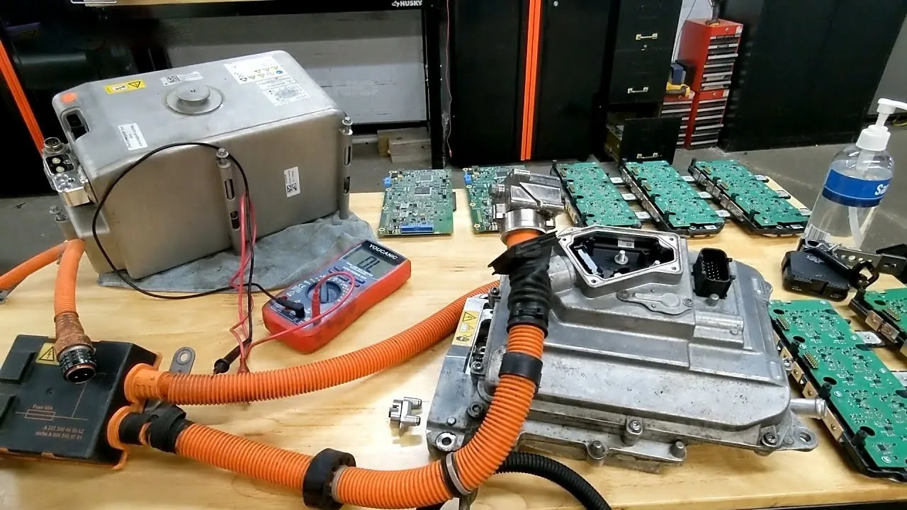 Tesla Model Y HVIL components, multimeter, and orange high-voltage cables on workbench