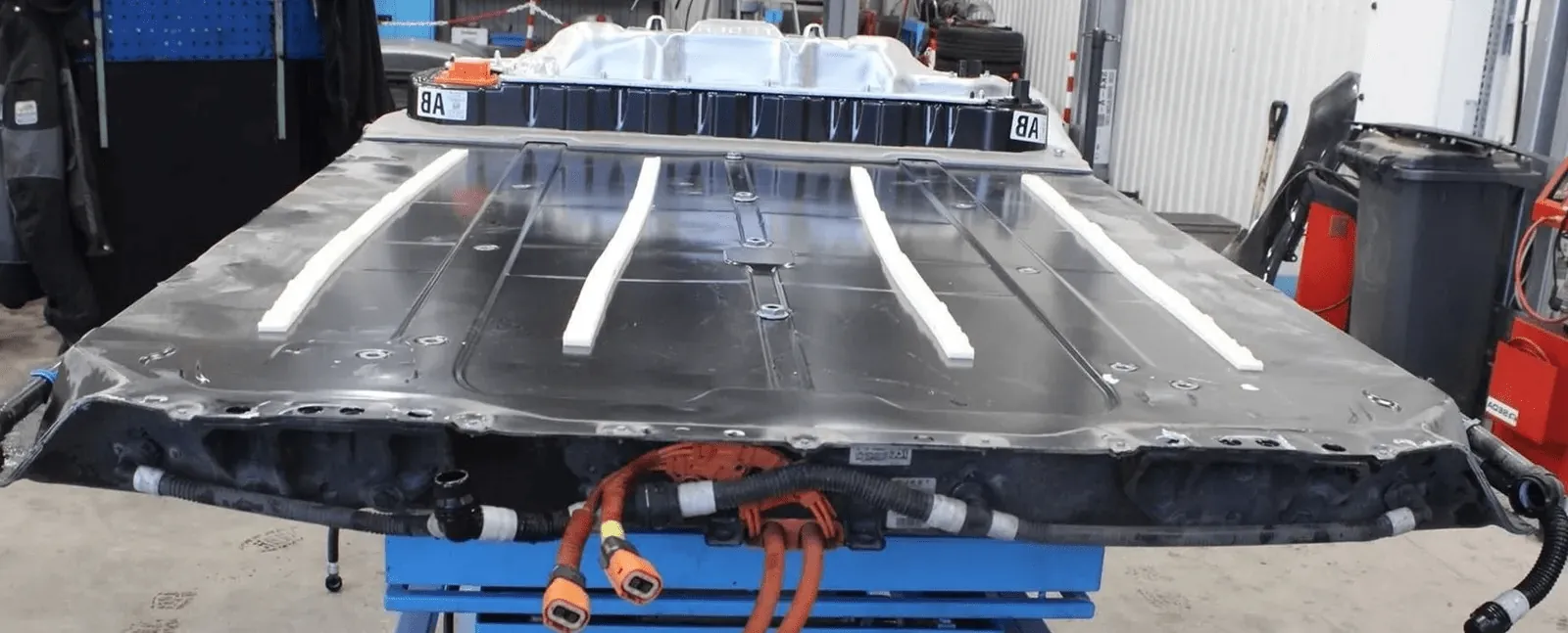 Tesla Model Y high-voltage battery pack removed, showing wiring and connectors at TSK