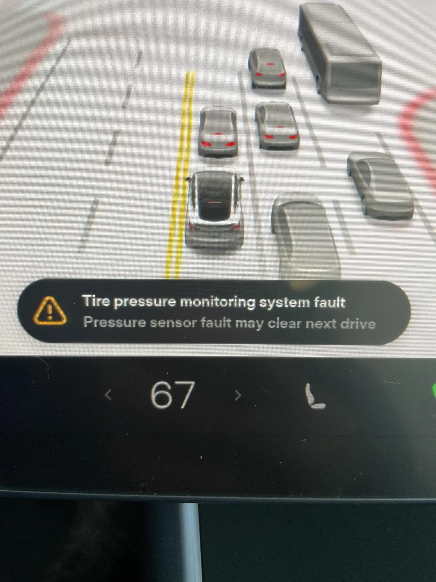 Tesla Model Y touchscreen showing tire pressure monitoring system fault warning at 67 mph