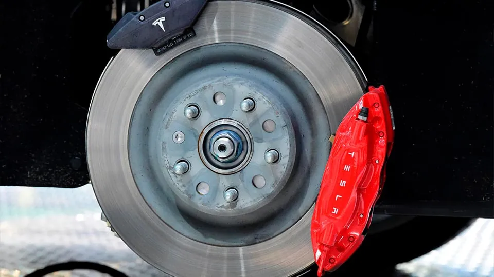 Tesla Model Y front brake rotor and red caliper during suspension repair at TSK