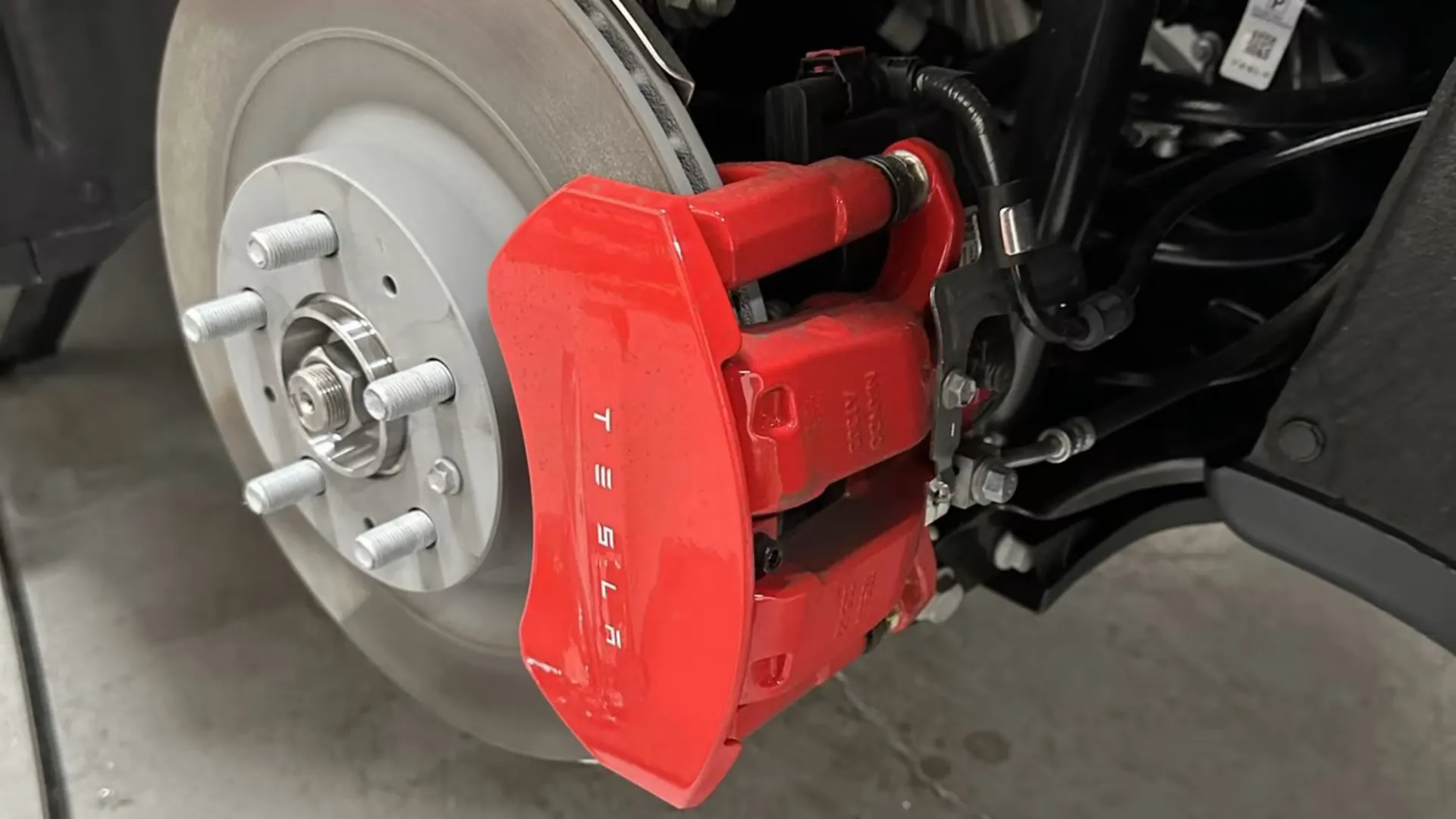 Red Tesla brake caliper and rotor exposed during service at TSK repair shop