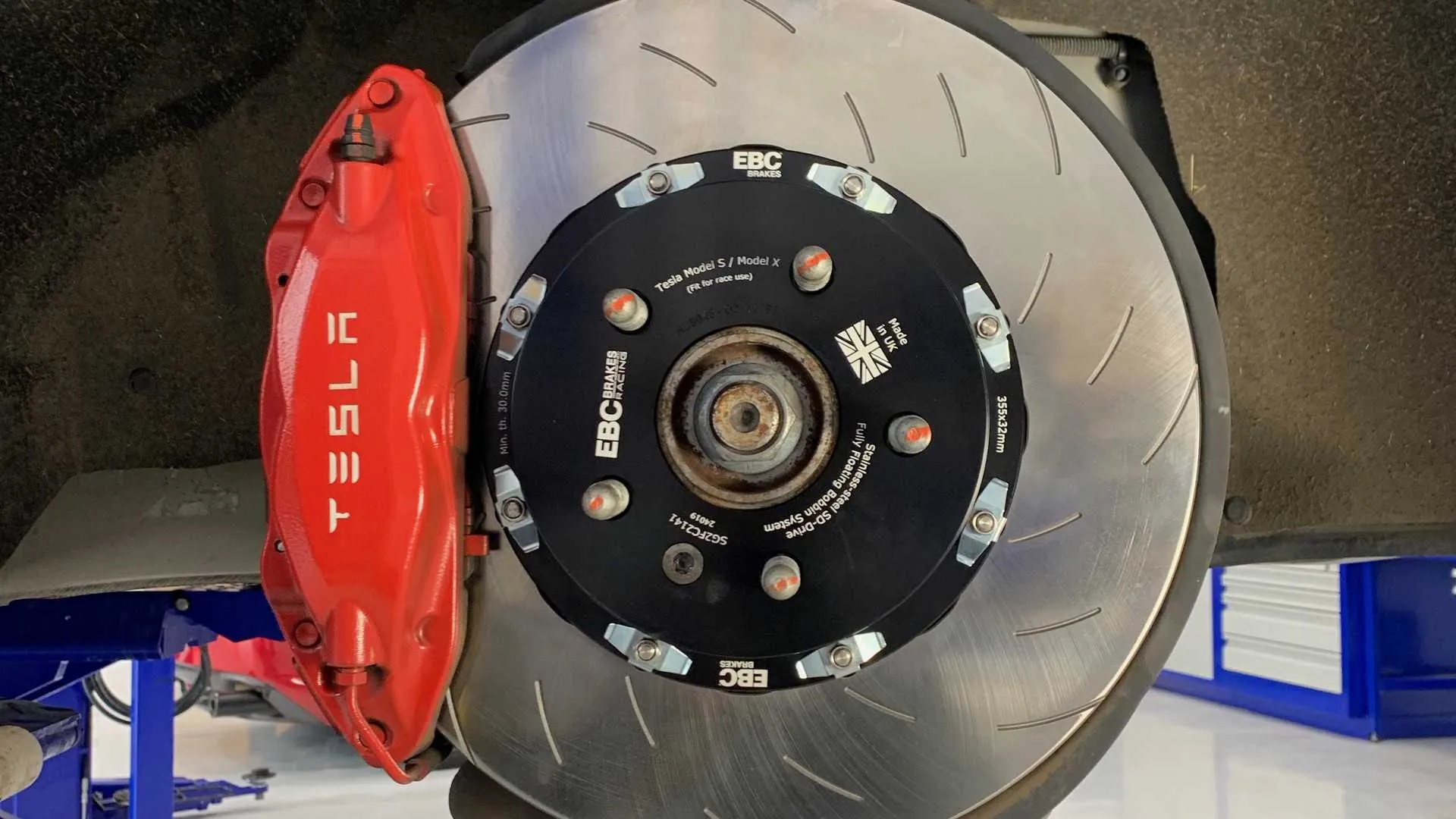 Tesla Model S/X red brake caliper with EBC slotted rotor during service at TSK
