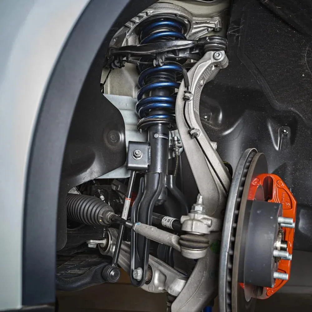 Tesla front suspension with blue coil spring, control arms, and orange brake caliper exposed