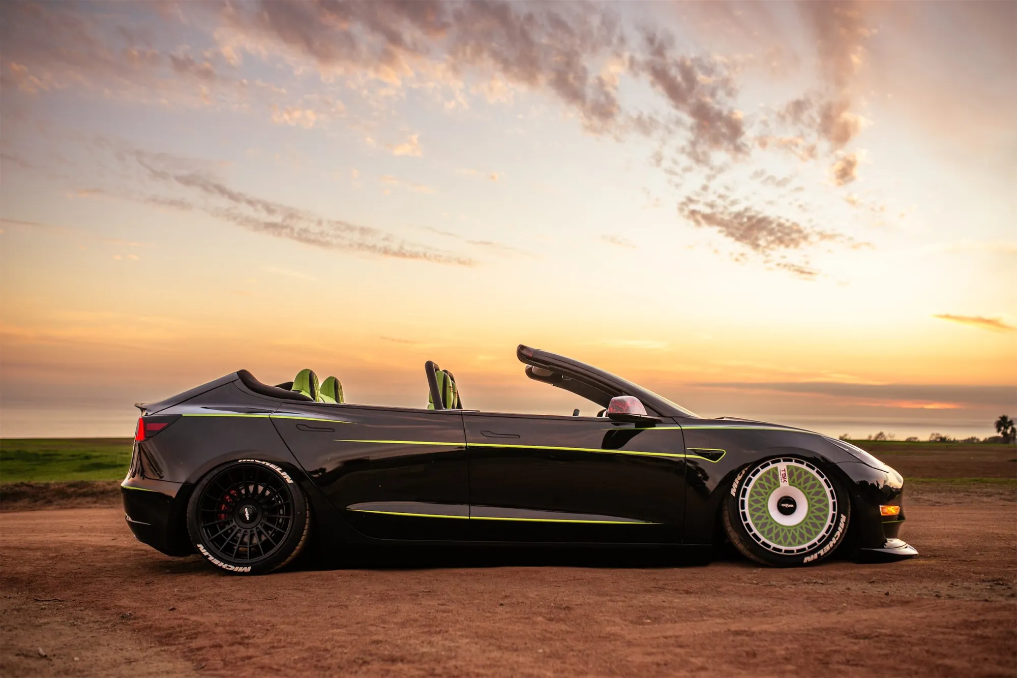 Roofless Tesla project: black Tesla Model 3 convertible with green stripes and a TSK wheel cover at sunset