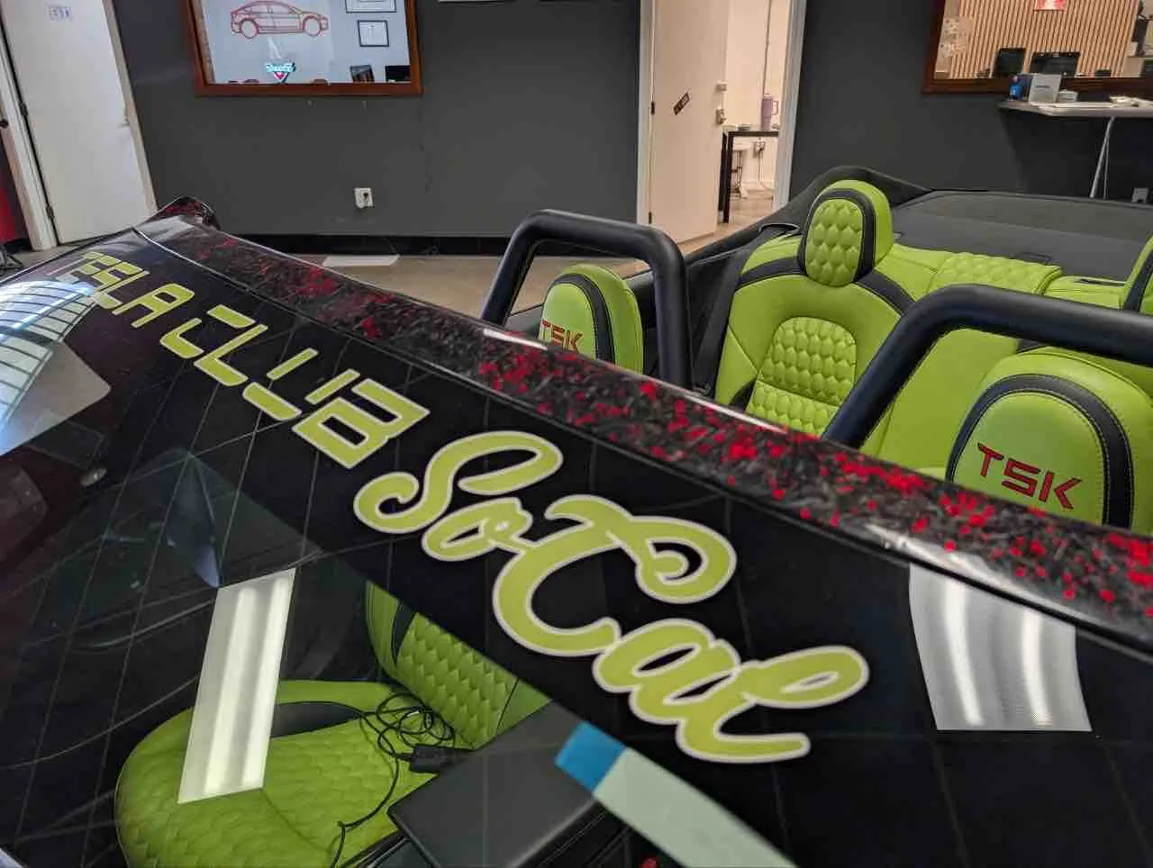 Roofless Tesla project: lime green TSK seats and roll bars in the open cabin at the TSK shop