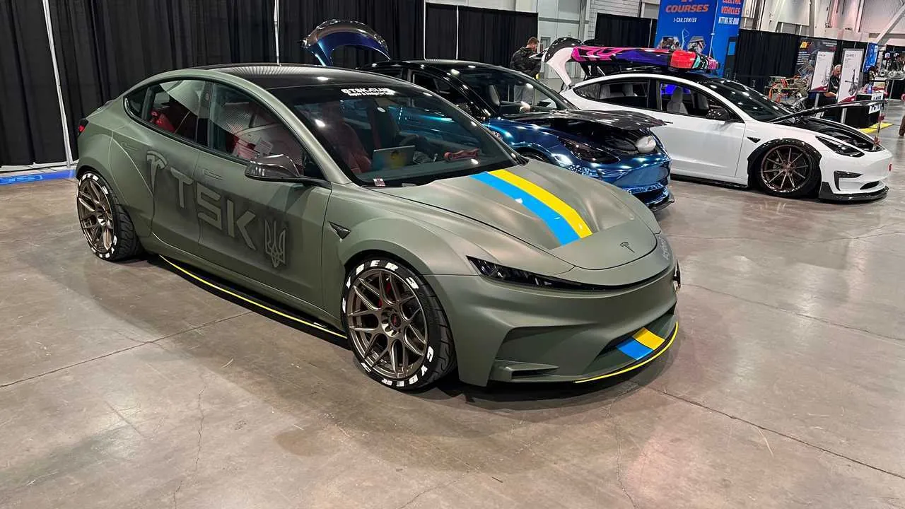 Cyber 3 project: matte green widebody Tesla Model 3 with a Ukrainian flag stripe at a car show display