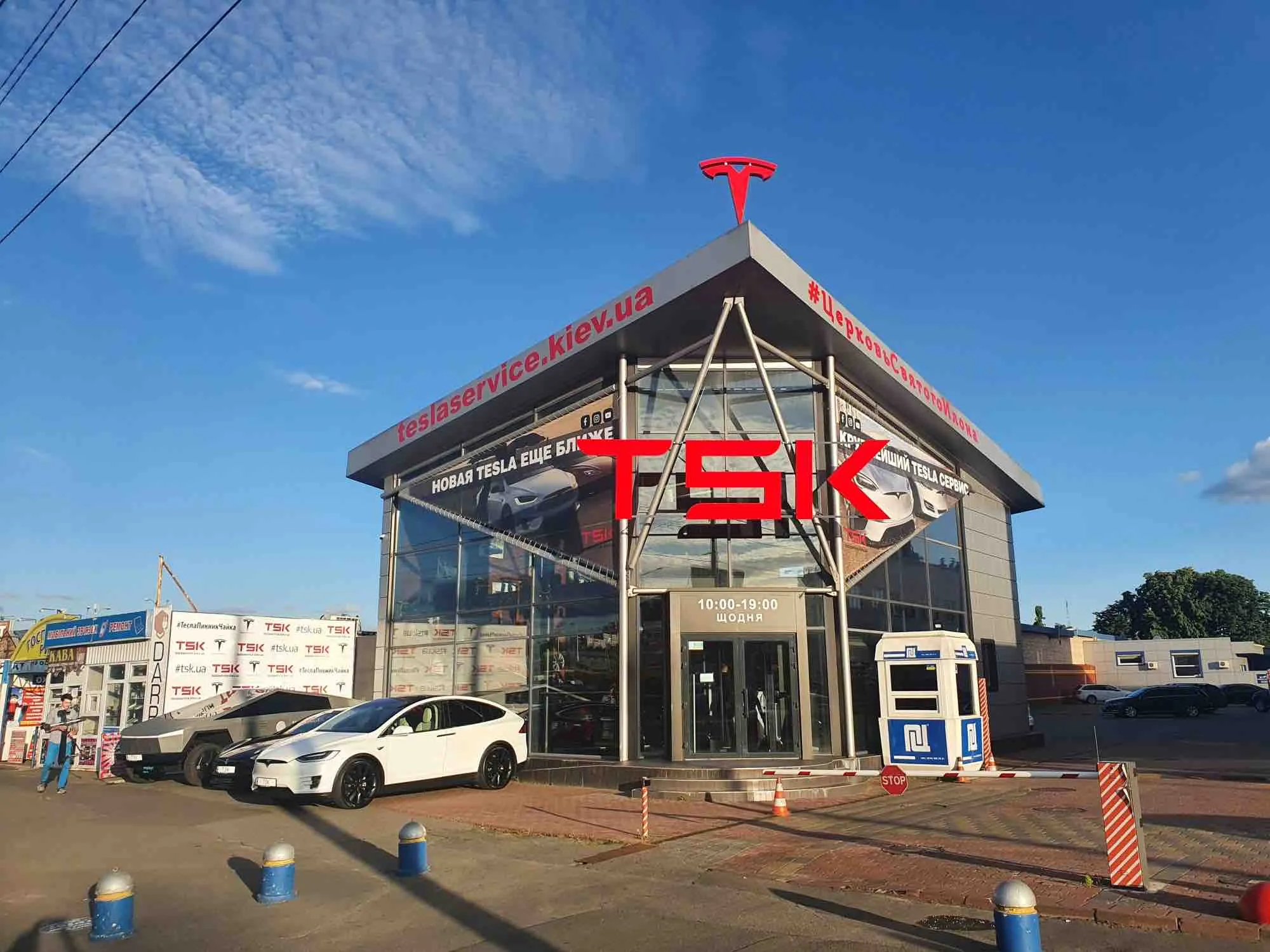 TSK Tesla service center building with Tesla logo, Cybertruck and Model X parked outside