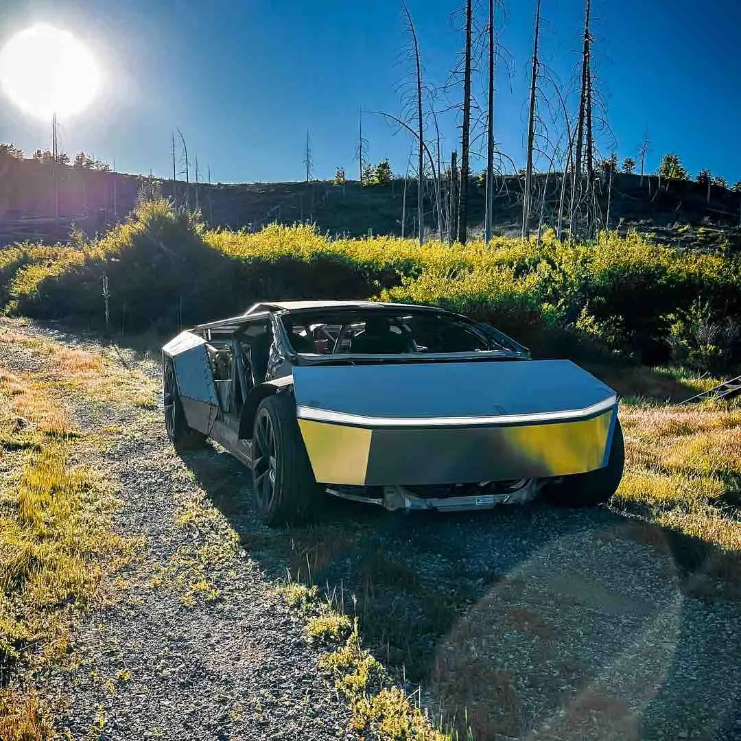 Custom stripped-down Tesla Cybertruck build parked on gravel path near burned forest