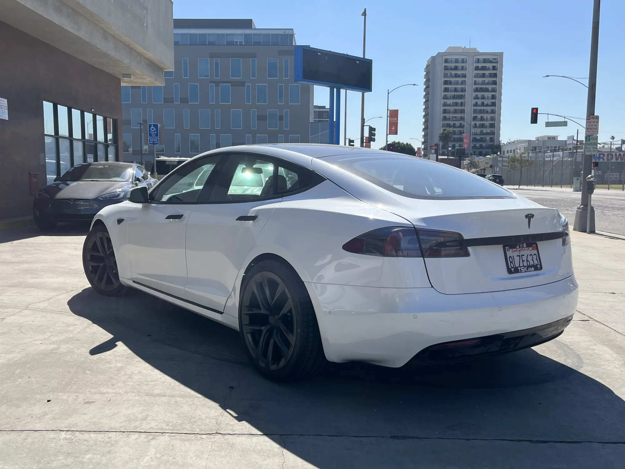 White Tesla Model S rear view parked outside TSK collision repair shop