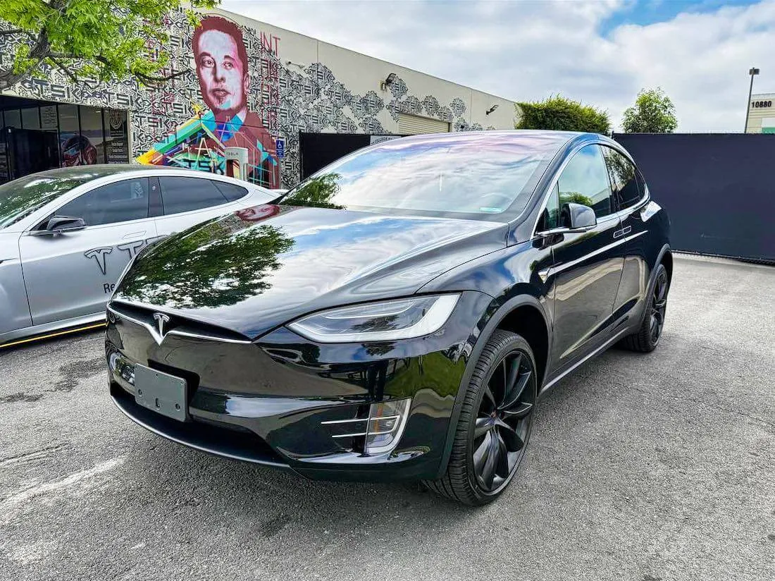 Black Tesla Model X parked outside TSK EV collision repair shop in California