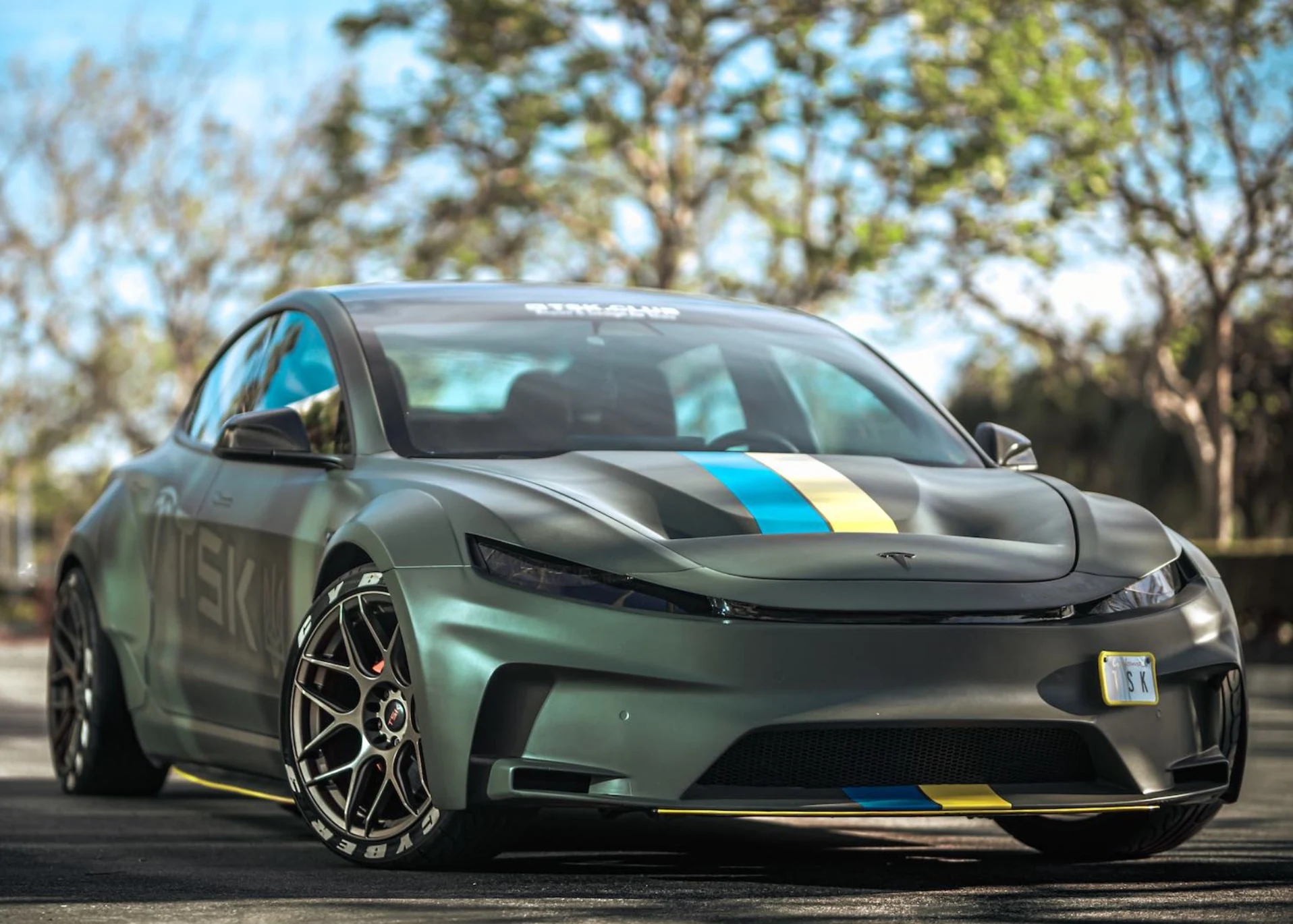 Cyber 3 project: matte green widebody Tesla Model 3 with blue and yellow hood stripes and bronze wheels