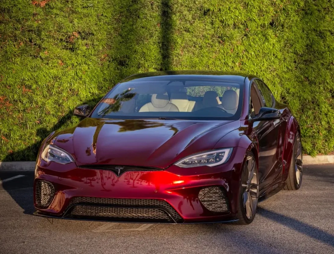 Wild Tesla project: dark red Tesla Model S widebody parked by a hedge